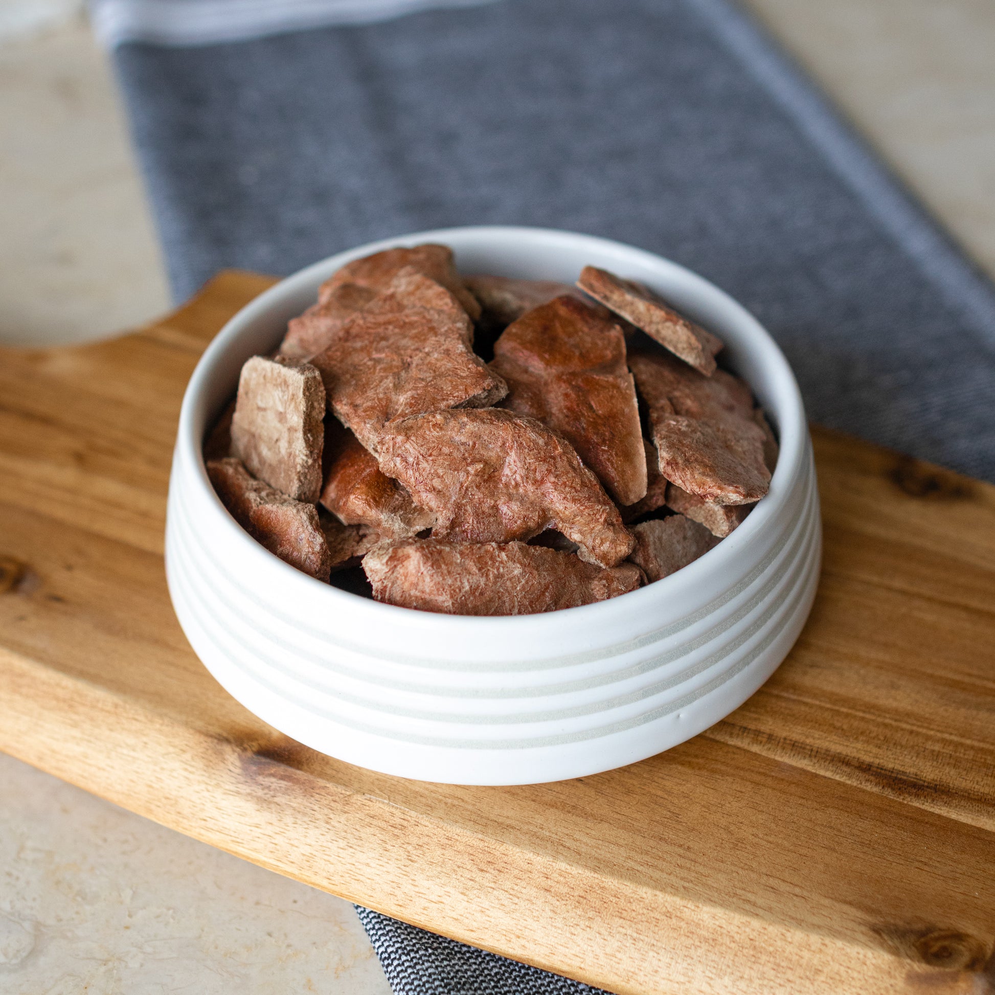 A bowl filled with Winni Treats Freeze Dried Raw Beef Liver dog treats, showcasing their natural texture perfect for dog snacks.