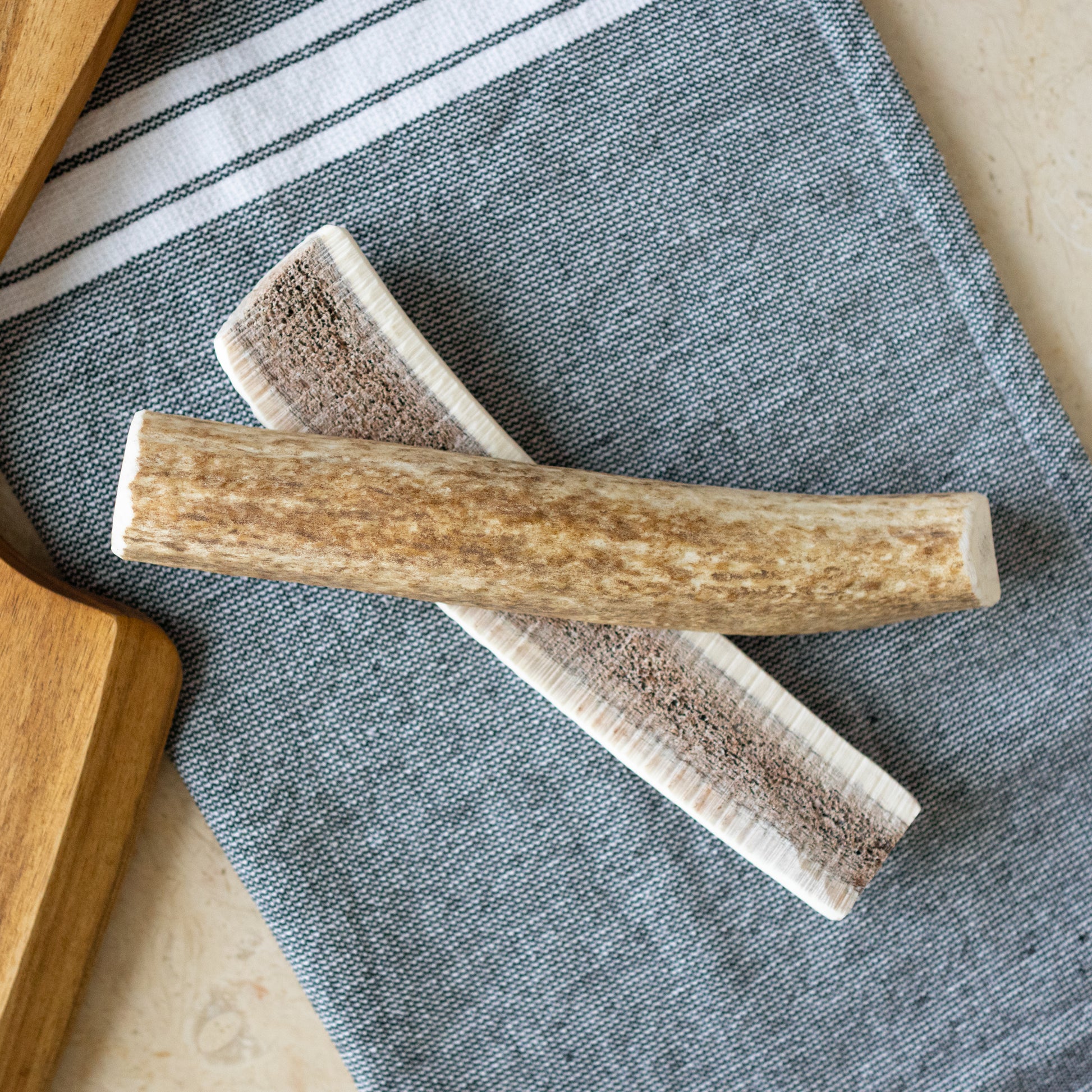 Naturally Shed Elk Antlers for Dogs - Two pieces of natural elk antlers on a grey towel, perfect for dogs to chew, promoting dental health and stress relief. Ideal long-lasting chew packed with nutrients.