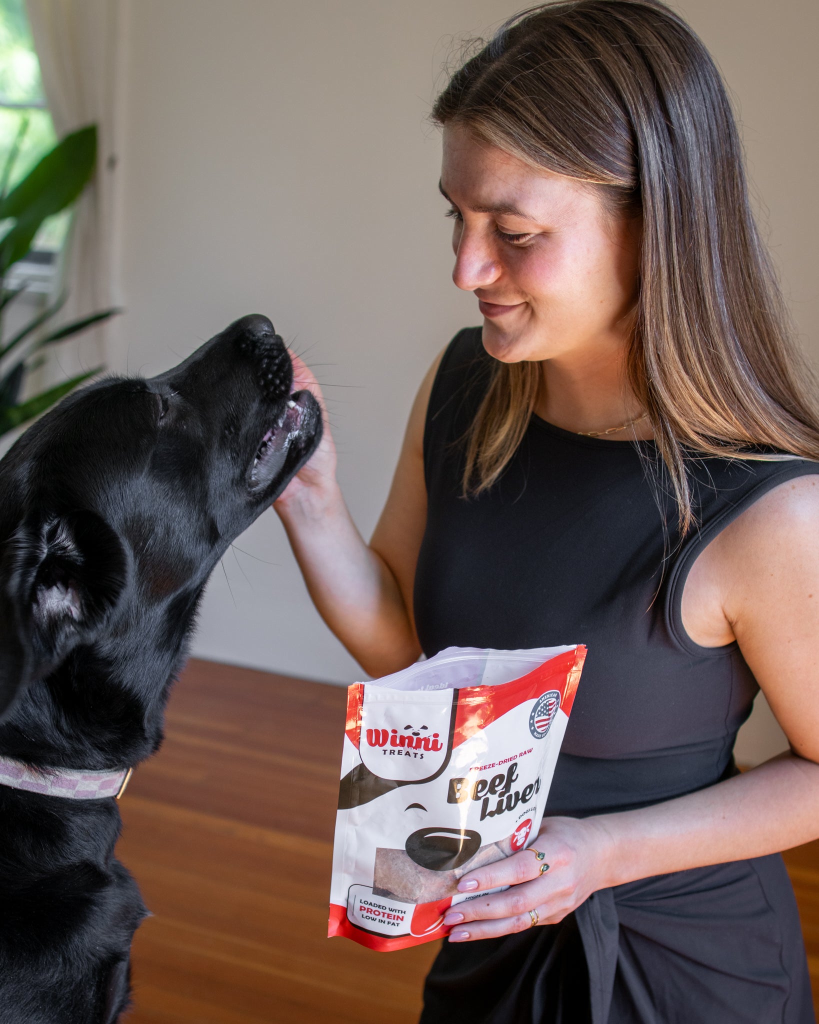 A happy dog and a woman sharing Winni Treats Freeze Dried Raw Beef Liver dog treats, highlighting their bonding moments with nutritious rewards.